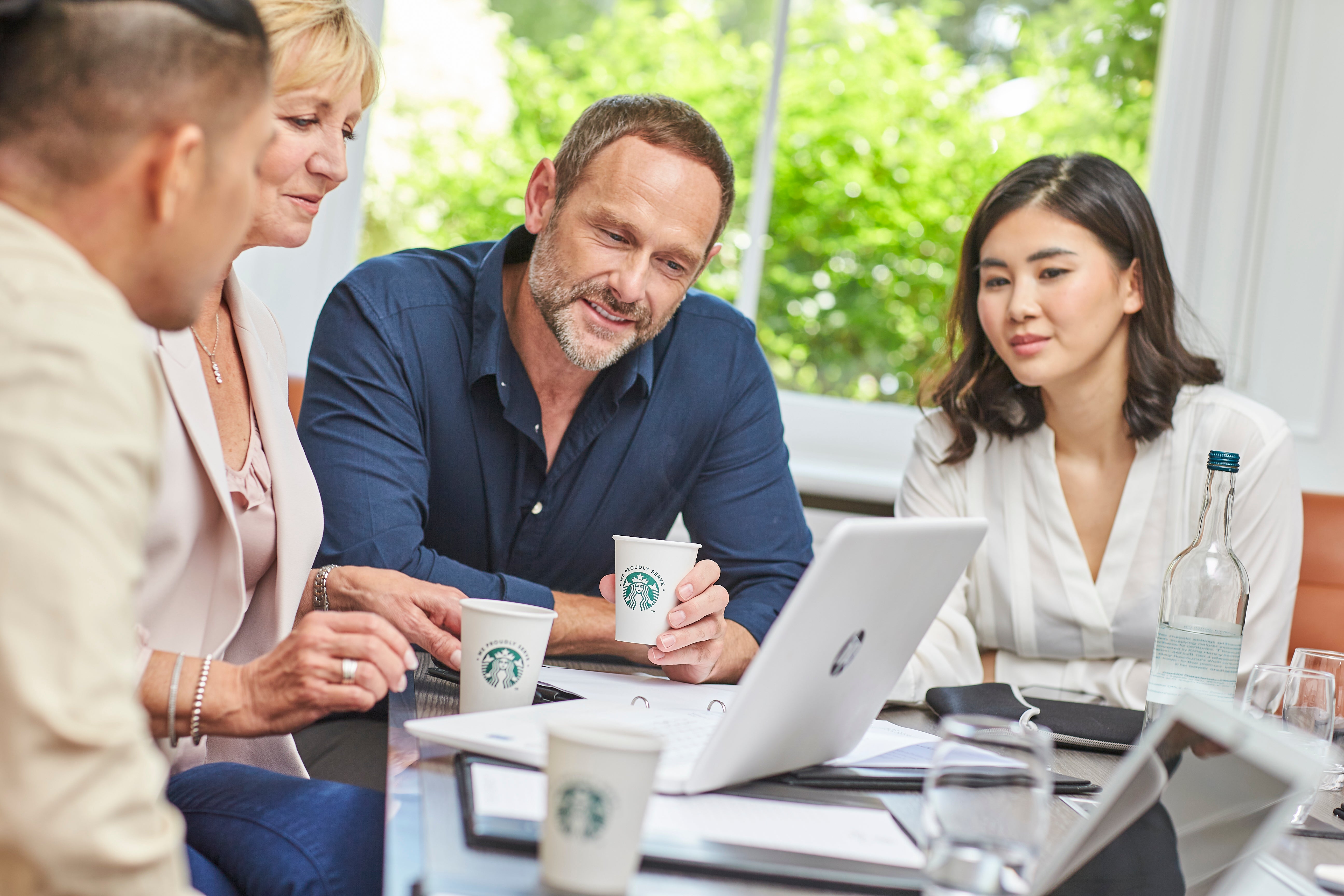 people drinking we proudly serve starbucks around a table