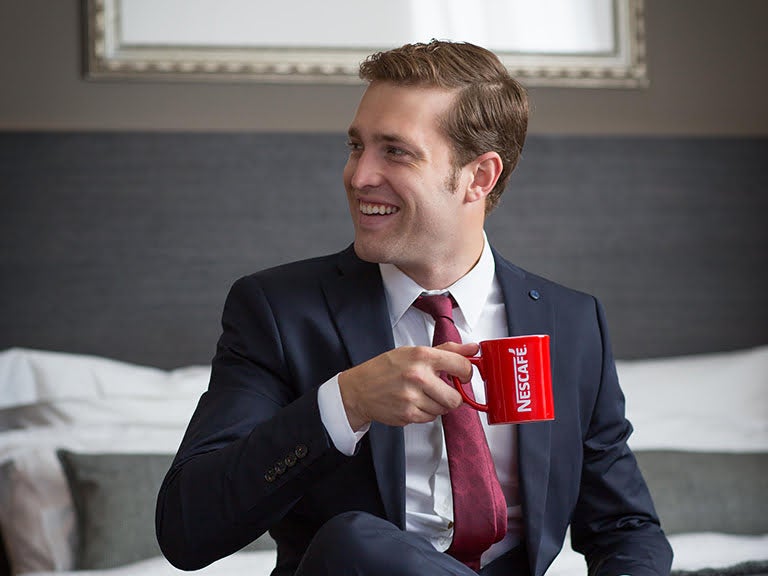 hotel guest in a suit enjoying a coffee, sitting on the bed