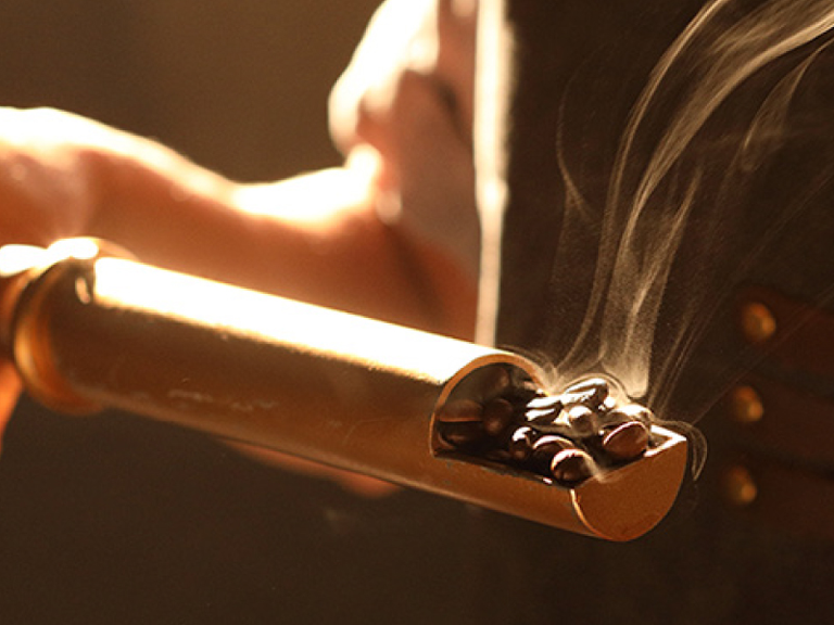 Steaming coffee beans on gold spoon