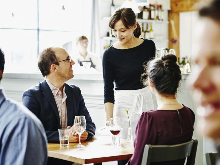 A waiter talking to two customers