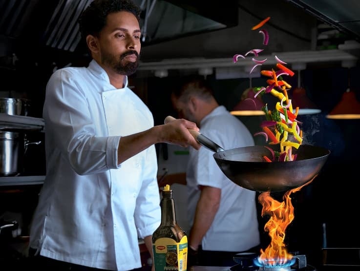 Chef with pan above a kitchen flame